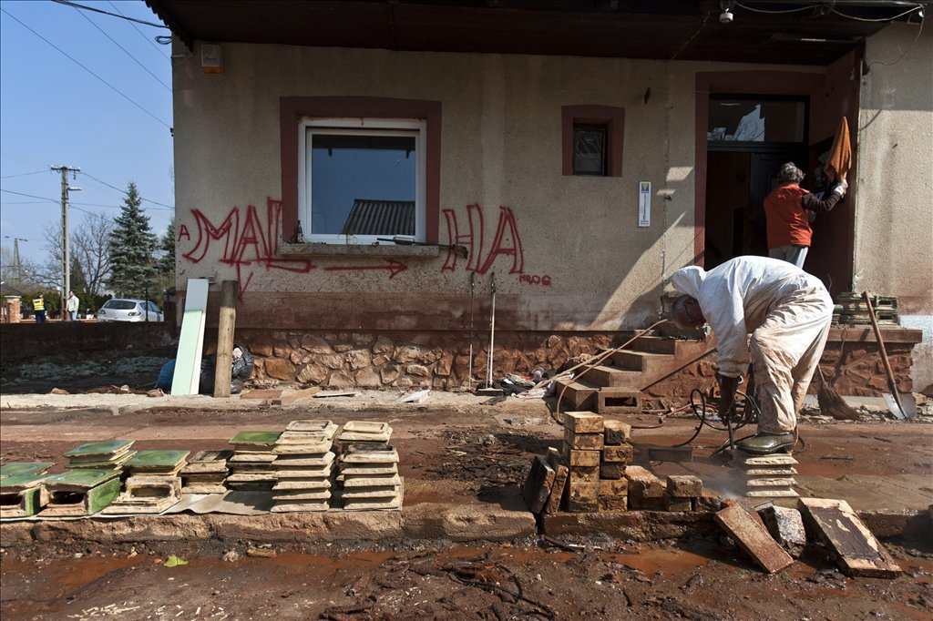 Cserépkályha csempéit tisztítja magasnyomású vízsugárral egy férfi egy bontásra váró családi ház udvarán