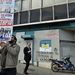 Egy athéni férfi újabb tüntetésekre mozgósító plakátot helyez el egy lámpaoszlopon az Aspis Bank  bezárt fiókjánál.