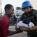 Bolíviai békefenntartó nyújt át egy csecsemőt az apjának.