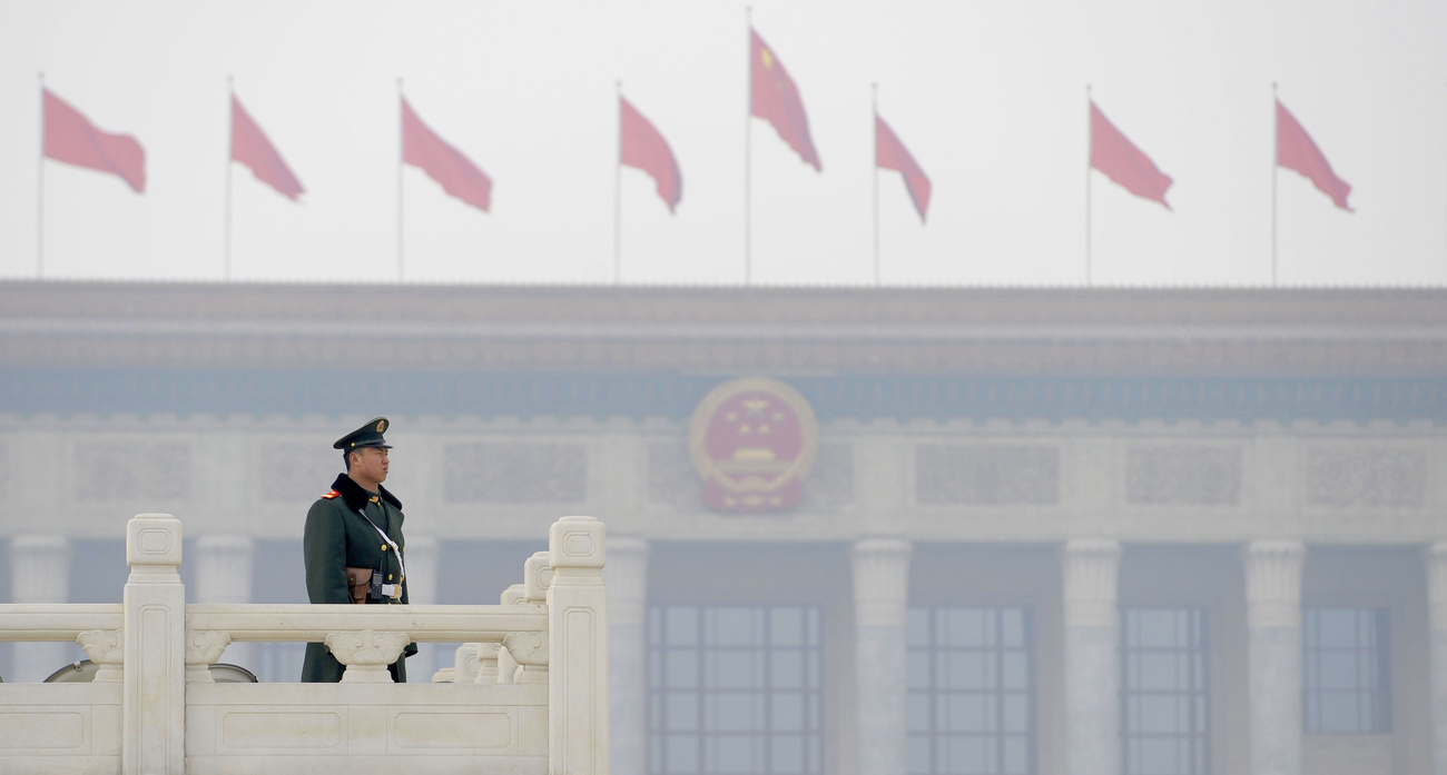 Délnyugat-kínai etnikai kisebbségek népviseletébe öltözött hoszteszekkel fényképezkedik egy rendőr a Tienanmen téren.