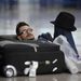 Egy férfi alszik a csomagjain a barcelonai El Prat reptéren.