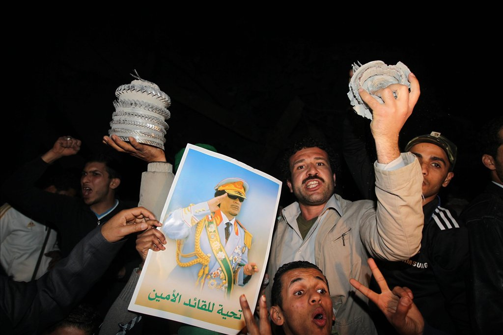 Líbia férfiak éltetik Moammer el-Kadhafi líbiai vezetőt a romok közt