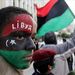 Egy fiú az arcára festve viseli a monarchia korabeli líbiai zászlót.