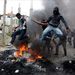Palesztin fiatalok kővel dobálnak izraeli katonákat egy felgyújtott barikádnál, a ciszjordániai Hebronban 