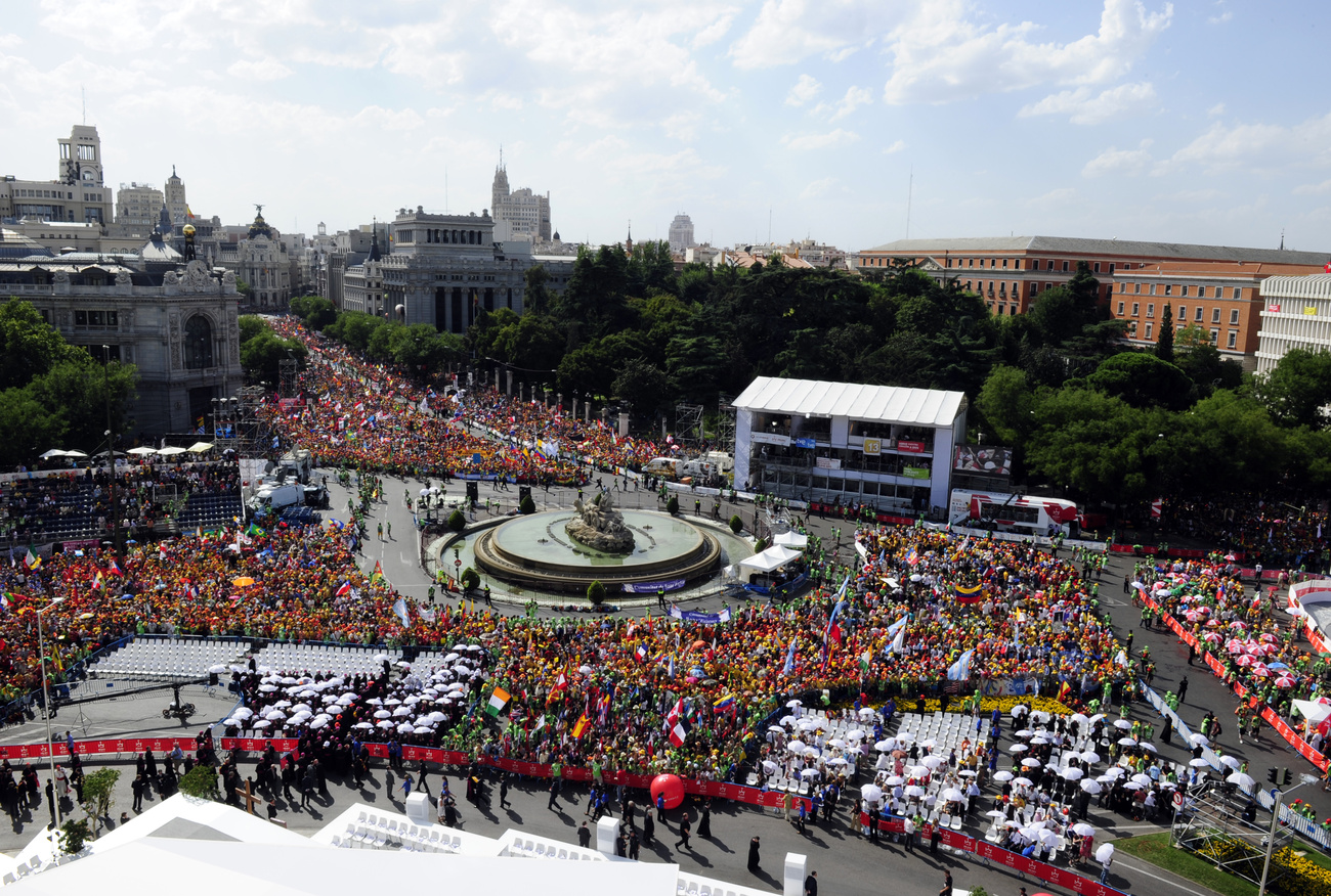 Pápaellenes tüntetők maroknyi csoportja és rendőrségi járművek a Puerta del Sol téren