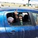 Egy líbiai kislány a győzelem jelét mutatja egy autóból.