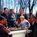 Idős férfiak koreai sakkot (jangki) játszanak egy phenjani közparkban. A zakók bal oldalán Kim Ir Szen kitűzők.