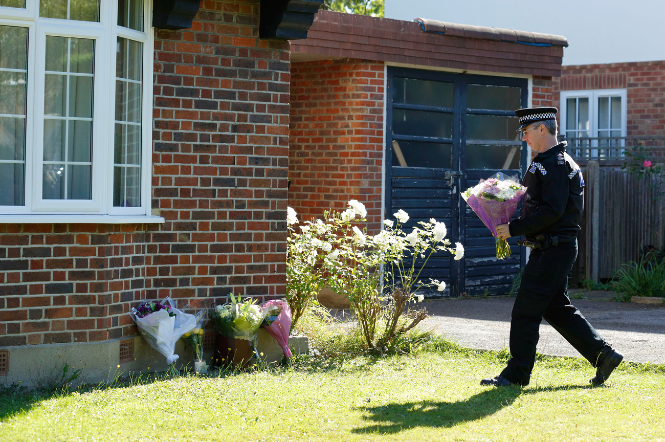 Rendőrök viszik a virágokat a lezárt al-Hilli házhoz.