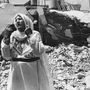 Lebombázott háza előtt áll egy nő a Gázai övezetben