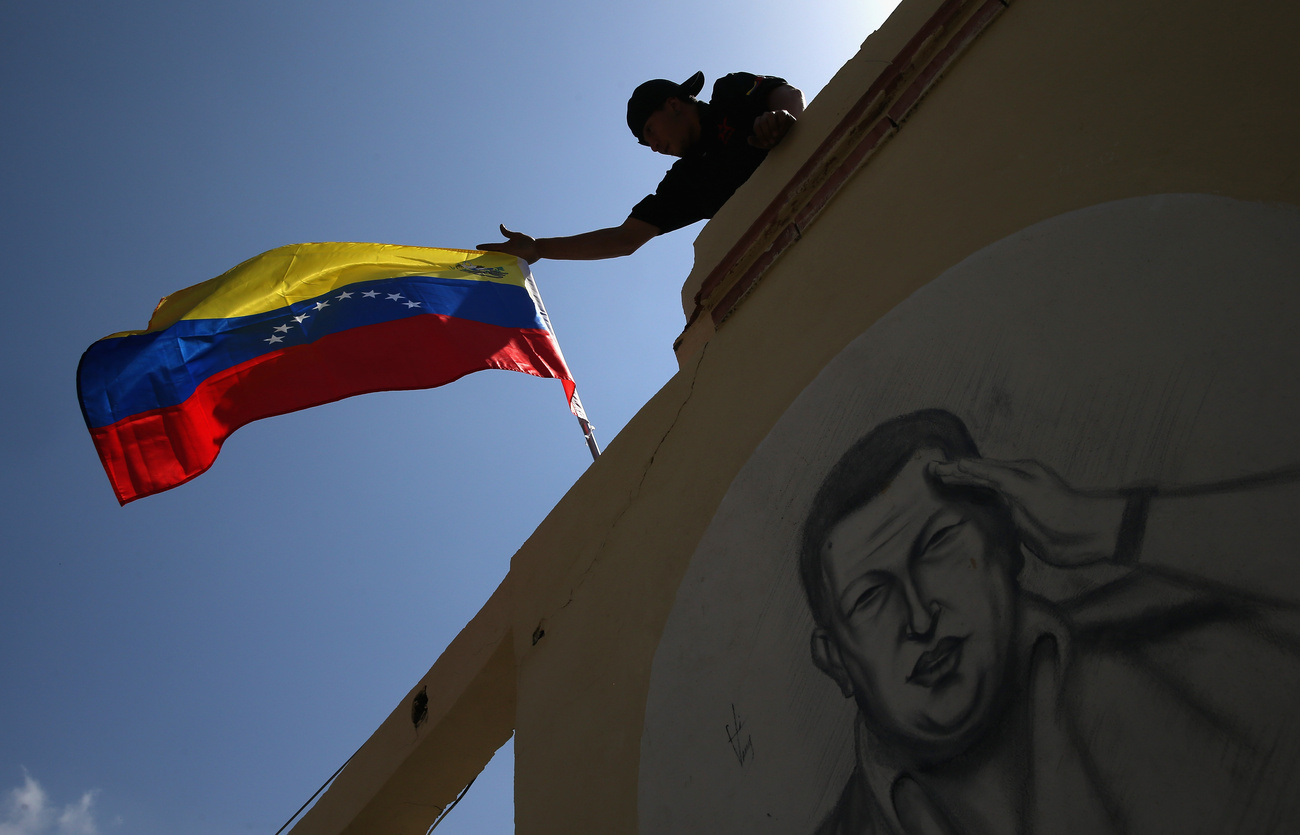 Chávez egyik híve zászlót tűz egy a volt elnök képével díszített falra, a 
