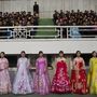 Észak-koreai népviseletbe öltözött nők a futópálya mellet.