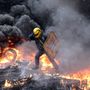 Lángoló roncsok között menekül egy ukrán tüntető Kijevben