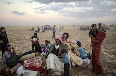 Bulent Kilic (középen) kurd menekülteknek mutatja a fotóit egy szíriai menekülttáborban.