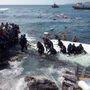 Illegális bevándorlók a Rodoszon fekvő Zefirosz tengerpartján 2015. április 20-án miután zátonyra futott az őket szállító hajó. A mintegy 200 menekültnek sikerült sértetlenül partot érni. 