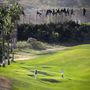 Golfozók játszanak a pályán Melillában, miközben menekültek másznak át mögöttük a határon
