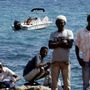 Egy férfi a csónakjából figyeli a parton várakozó menekülteket az olasz-francia határnál.