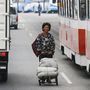 Buszok között tolja a kosarát egy nő a főváros egyik forgalmasabb utcáján