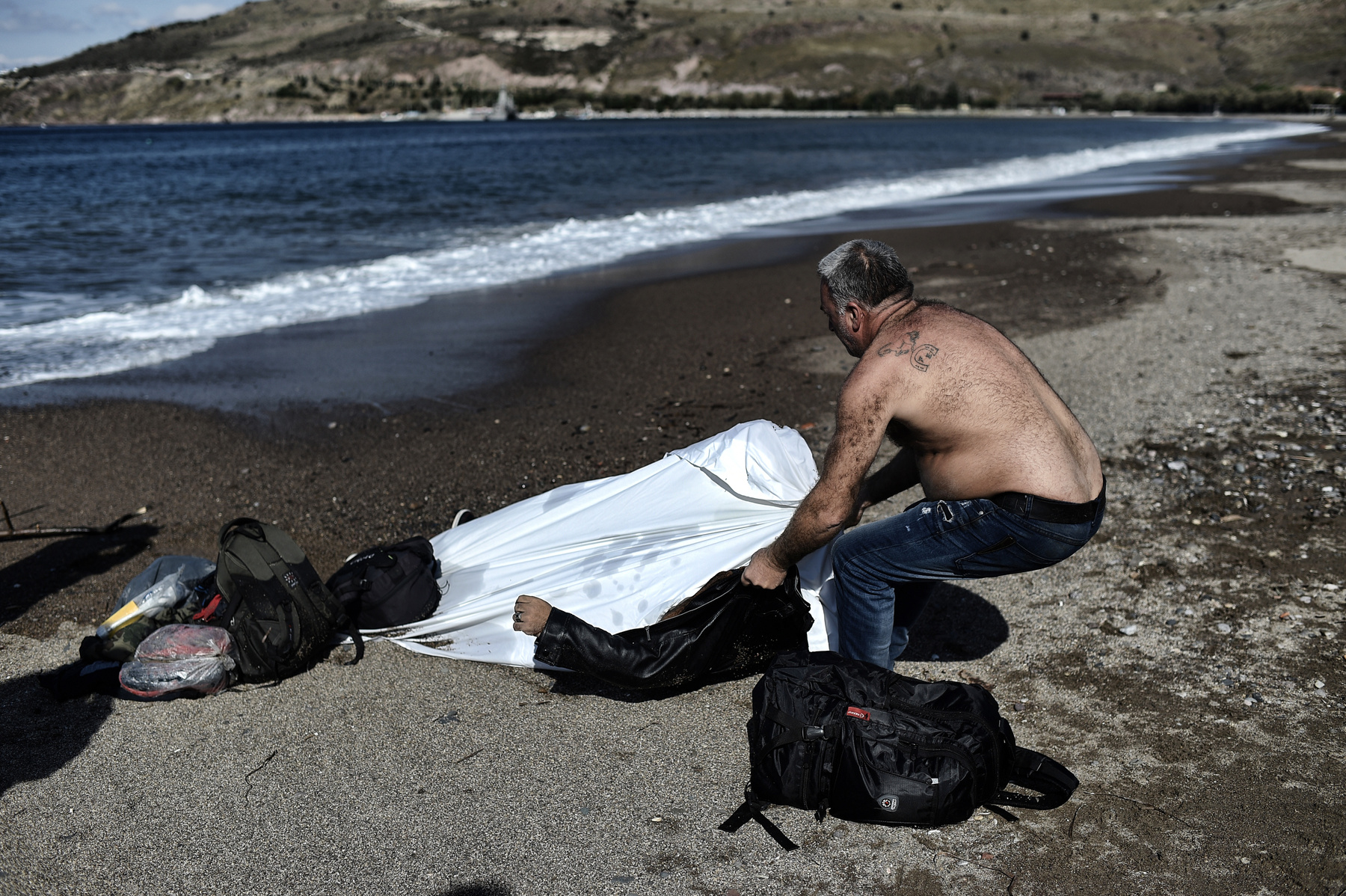 Egy helyi lakos holttestet húz a partra Leszbosznál