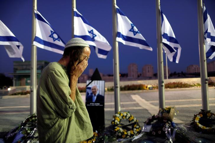 Az Izraeli Védelmi Minisztérium katonái szórnak homokot Peresz sírhelyére