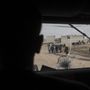 Egy katona nézi járművéből a harcok miatt otthonukból távozni kényszerült gyalogló embereket.