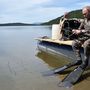 Vlagyimir Putyin orosz elnök búvárruhában ülve lándzsa horgászatra készül egy hegyi tóban 