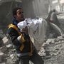 Egy szíriai férfi egy romok közül élve kiemelt csecsemőt tart a kezében. 