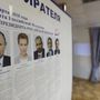 Az elnökválasztáson újra induló Vlagyimir Putyin hivatalban levő orosz államfő (b) és vetélytársai portréja egy szavazóhelyiségben