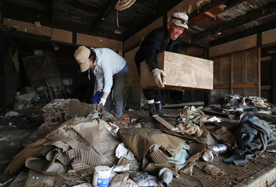 Egy elárasztott házból hordják ki a használhatatlanná vált ingóságokat Okajama prefektúrában