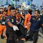 A mentőcsapat tagjai a gép egyik utasának maradványait viszik Jakarta kikötőjében.