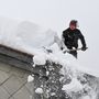 Inzellben lapátolja egy férfi a havat a háza tetejéről