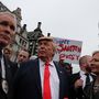 Egy tüntető Donald Trumpnak öltözve sétál a menetben a Trafalgar Square-nél. A jellegzetes hajviselet és a narancsos arcbőr mellett odafigyelt a megfelelő, piros színű nyakkendőre, és még kamu biztonsági kíséretet is hozott magával.