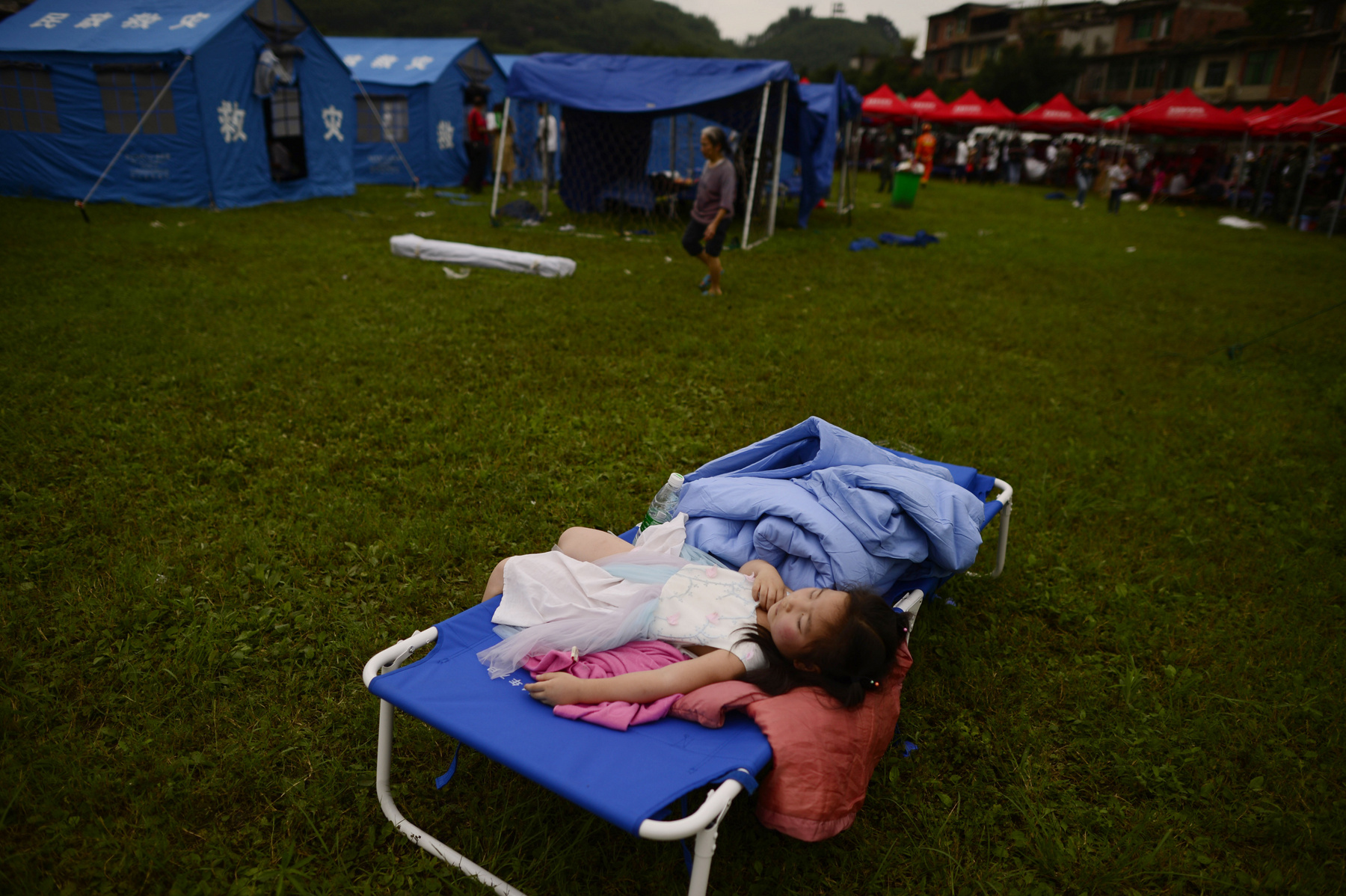 Emberek állnak sorban ételért és vízért a földrengés túlélőinek létrehozott ideiglenes sátraknál Yibinben 2019. június 18-án