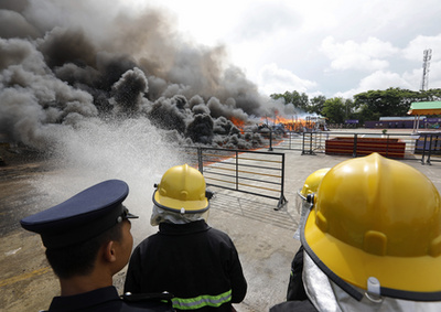 Mianmari tűzoltó korlátozza a lángok terjedését egy drogégetésen Rangunban 2019. június 26-án