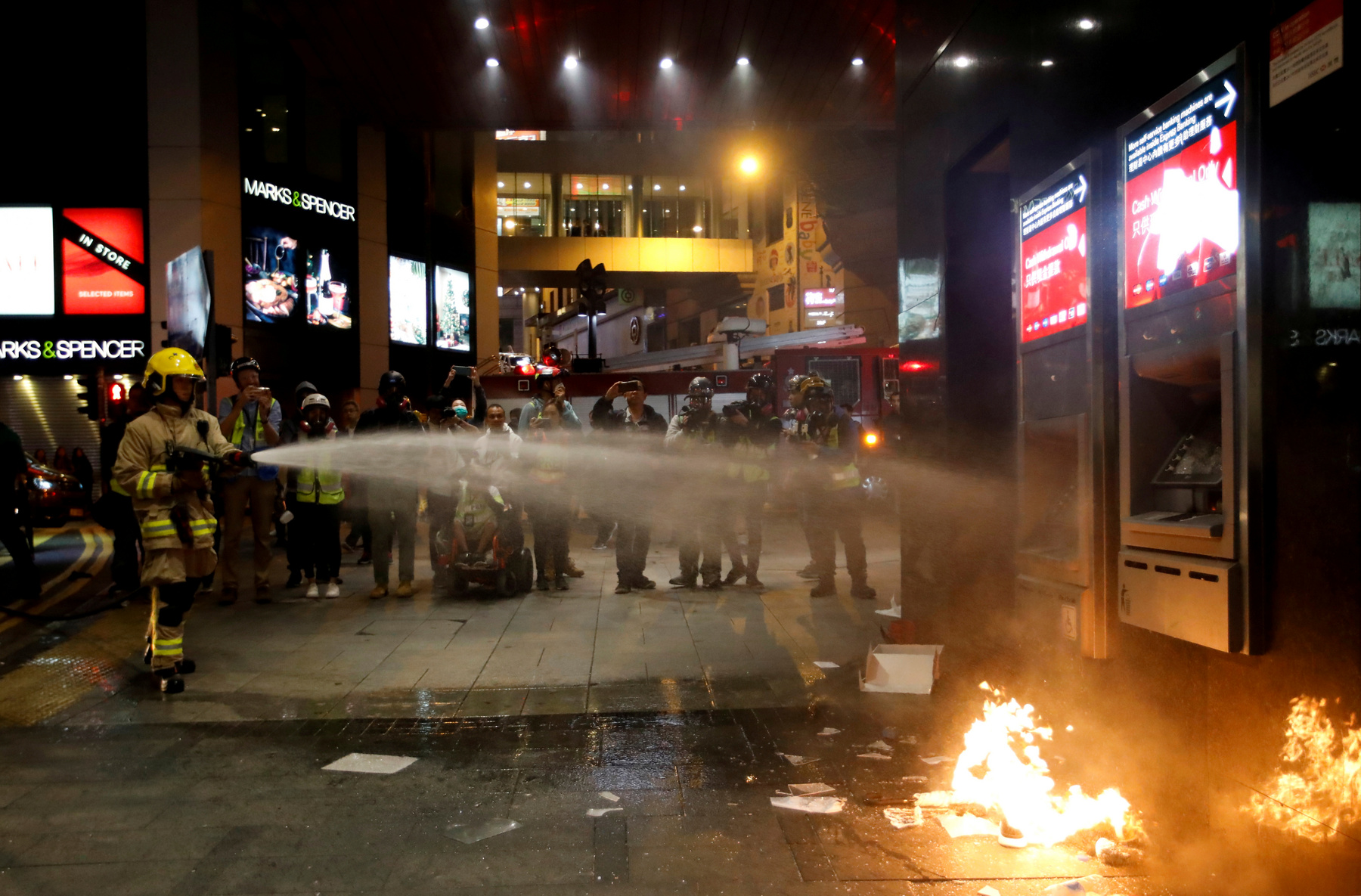 Tűzoltó oljta a felgyújtott ATM-et Hongkongban 2020. január 1-én