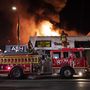 Egy tüntetők által felgyújtott és kifosztott üzletnél dolgoznak a tűzoltók a Los Angeles-i Melrose sugárúton 2020. május 30-án.