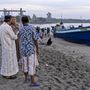 Helyi lakosok néznek egy hajót amin rohingja nemzetiségû muzulmánok érkeztek az indonéziai Aceh tartomány Lhokseumawe településének tengerpartjára  2020. szeptember 7-én