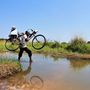 Az UNICEF munkatársa kerékpárját megemelve keresztez egy mocsárt, hogy a védőoltásokat eljuttassa az anarcho-kommuniszitkus állapotokat mutató Kongói Demokratikus Köztársaság legtávolabbi egészségügyi zónájába, Manonoba.