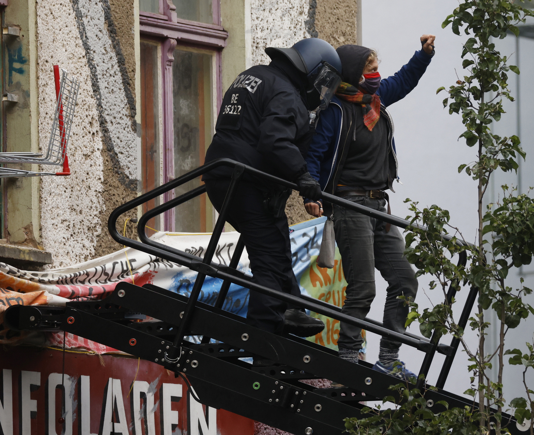 A rendőrség által kitessékelt tüntető emeli fel öklét a berlini Liebig utca 34-nél