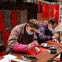 Újévi jókívánságokat festenek szerencsét hozó, piros papírra Hongkongban. A kalligráfia a legfontosabb, hagyományos művészeti forma a kínai kultúrában, ezért minden ünnep kísérőeleme. 