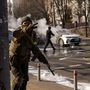 Ukrán katonák egy katonai létesítmény közelében, miközben két autó ég egy kijevi utcán 2022. február 26-án
