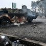 Fegyveres férfi sétál egy kiégett katonai jármű mellett a Kijevhez közeli Brovai városában 2022. március 1-jén