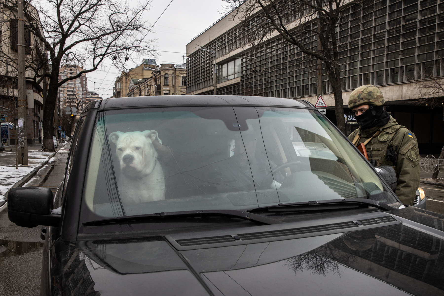 Fegyveres férfi sétál egy kiégett katonai jármű mellett a Kijevhez közeli Brovai városában 2022. március 1-jén