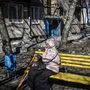 Nő ül egy elpusztított ház közelében Harkivban 2022. február 24-én