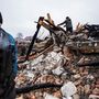 A helyi lakosok az ágyúzástól megsemmisült lakóépület maradványai között dolgoznak Zsitomirban 2022. március 2-án