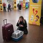 Egy nő a bőröndjével és egy macskahordozóval, miközben telefonál a kijevi metróállomáson 2022. február 24-én
