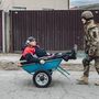 Egy idős embert tol talicskában egy katona Irpiny városának evakuálása közben 2022. március 5-én