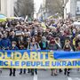 A tüntetők Szolidaritás az ukrán néppel feliratú plakátot tartanak Franciaországban 2022. március 12-én