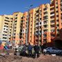 Emberek egy támadásban megrongálódott lakóépület mellett Harkivban 2022. március 18-án