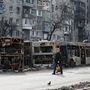 Egy helyi lakos sétál az utcán kiégett buszok mellett Mariupol déli városrészében 2022. április 19-én