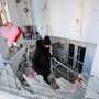 Egy nő takarítja a törmeléket egy lakóépületben található kávézóból Donyeckben 2022. december 6-án